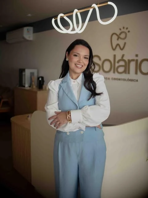 Proprietária da Solário na recepção da clínica, com o logotipo ao fundo.